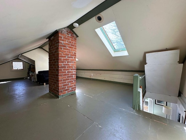 additional living space with vaulted ceiling with skylight and concrete flooring