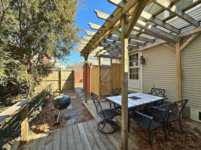 deck with outdoor dining space, a storage unit, fence, and a pergola