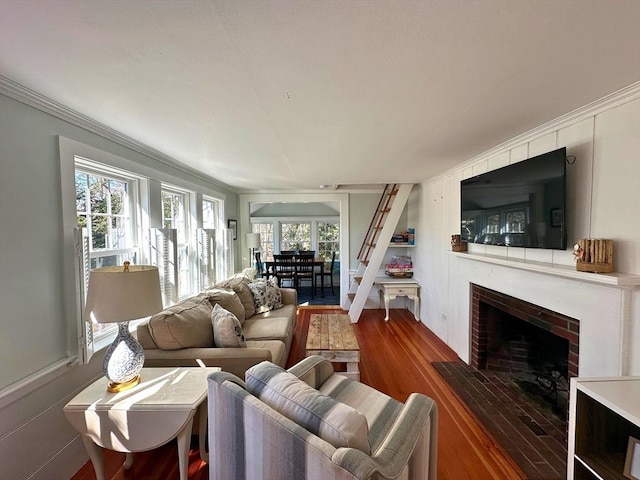 living area with a brick fireplace, wood finished floors, and ornamental molding