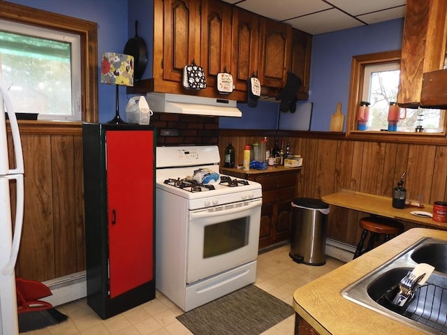 kitchen with wainscoting, white appliances, light floors, under cabinet range hood, and a baseboard heating unit
