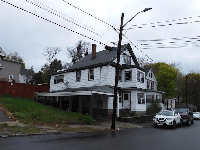 view of front of home with fence, a chimney, and a shingled roof