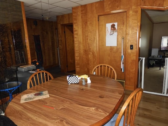 dining room with wood walls, wood finished floors, and a paneled ceiling
