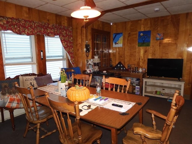dining area featuring a paneled ceiling and wooden walls