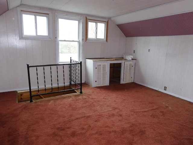bonus room with carpet, lofted ceiling, and wooden walls