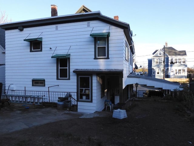 back of house featuring fence and a chimney