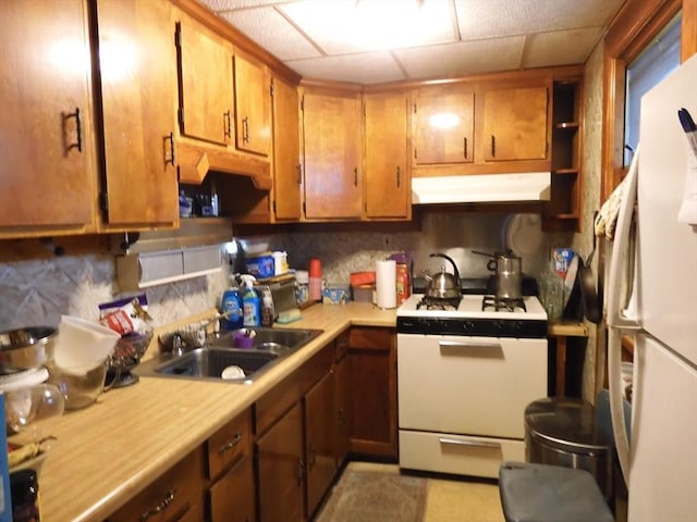 kitchen featuring a sink, white appliances, light countertops, tasteful backsplash, and under cabinet range hood