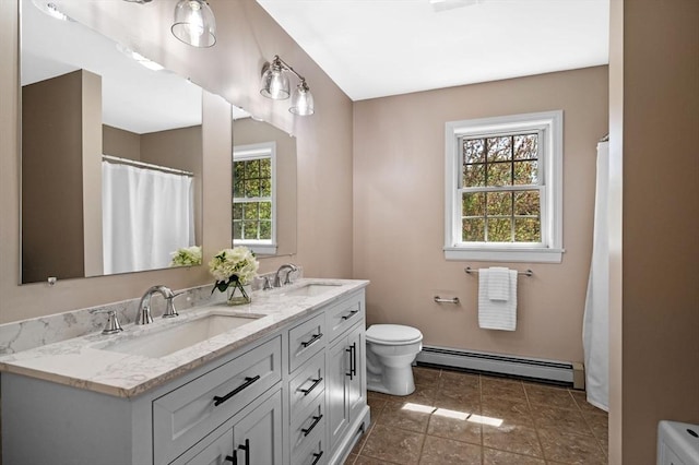 bathroom with a baseboard heating unit, toilet, and double vanity