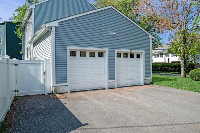 garage with asphalt driveway and fence