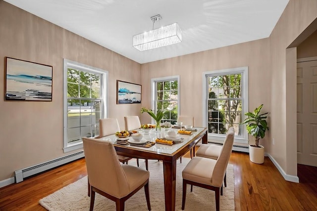 dining space featuring a baseboard heating unit, light wood-style flooring, and baseboards