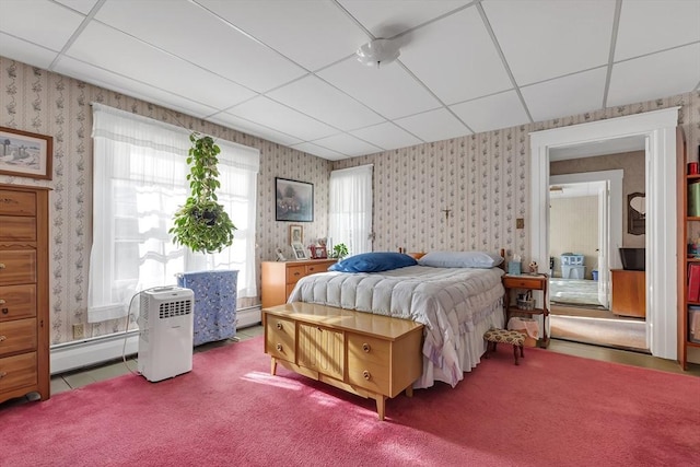 carpeted bedroom with a baseboard radiator and a drop ceiling