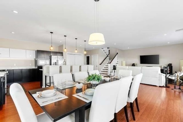 dining space featuring wood finished floors, recessed lighting, and stairs