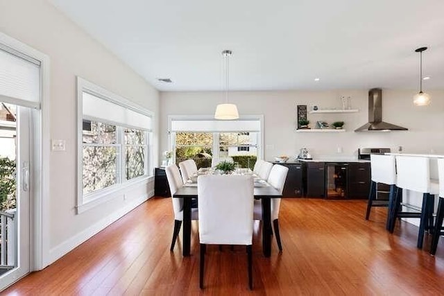 dining space with wood finished floors, baseboards, and wine cooler