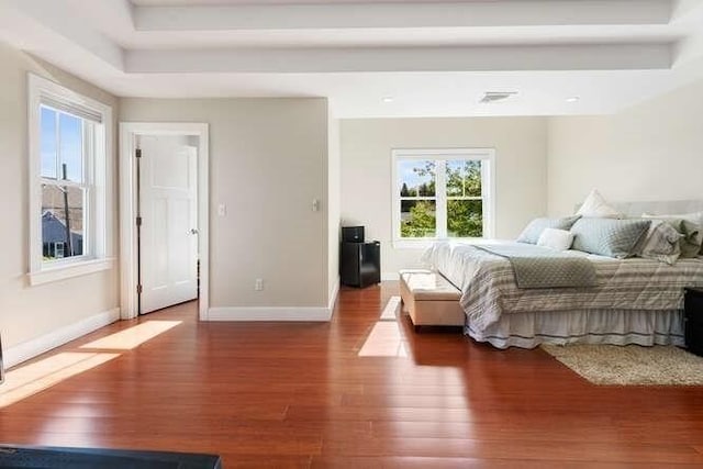 bedroom featuring wood finished floors, baseboards, and a raised ceiling