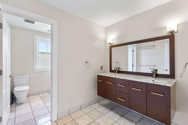 bathroom featuring double vanity, toilet, and baseboards