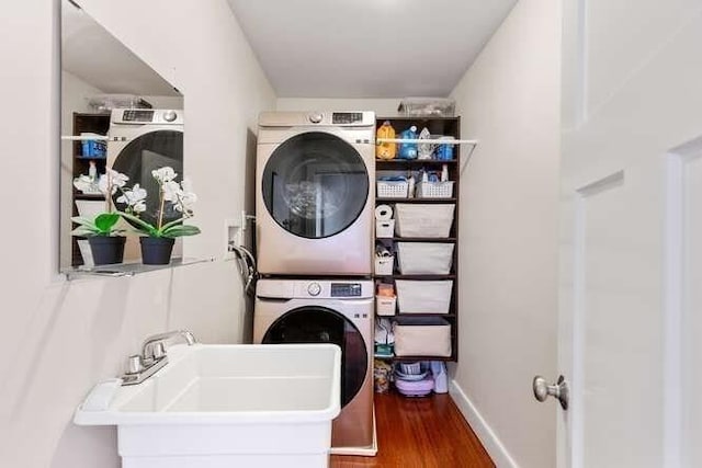 washroom with stacked washer / drying machine, wood finished floors, and baseboards