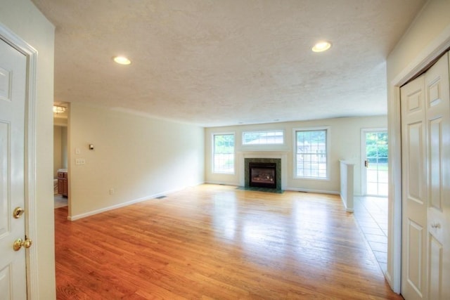 unfurnished living room with a textured ceiling and light hardwood / wood-style floors