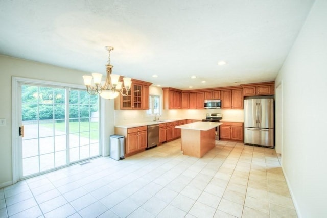 kitchen featuring a kitchen island, sink, hanging light fixtures, light tile patterned floors, and stainless steel appliances