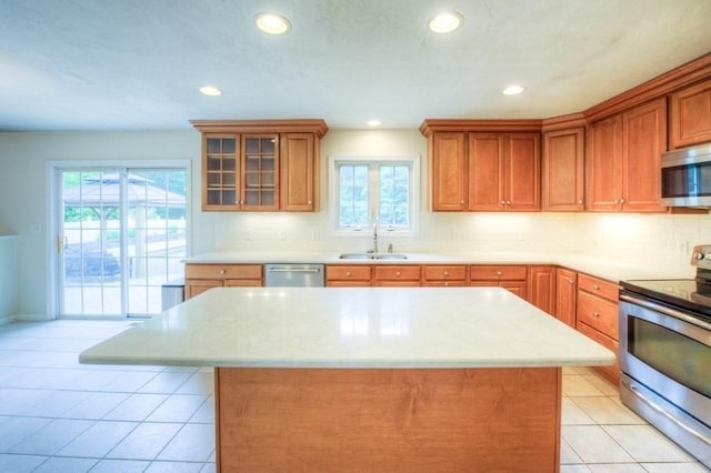 kitchen with sink, light tile patterned floors, stainless steel appliances, and a center island