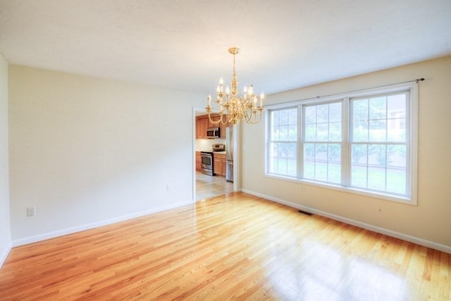 unfurnished room with light hardwood / wood-style floors and a notable chandelier