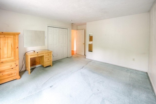 unfurnished bedroom with light colored carpet and a closet