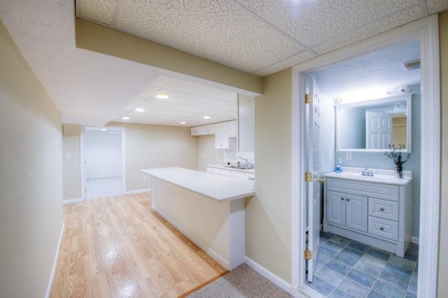 interior space featuring vanity, wood-type flooring, and a drop ceiling