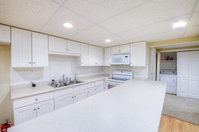 kitchen with a paneled ceiling, sink, white cabinets, light hardwood / wood-style floors, and white appliances