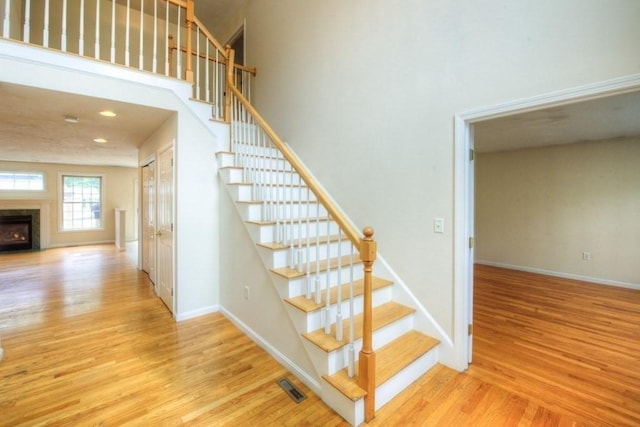 stairs with hardwood / wood-style floors and a high end fireplace