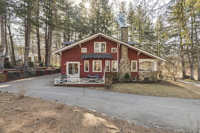 chalet / cabin featuring a front yard, a wooden deck, and a chimney