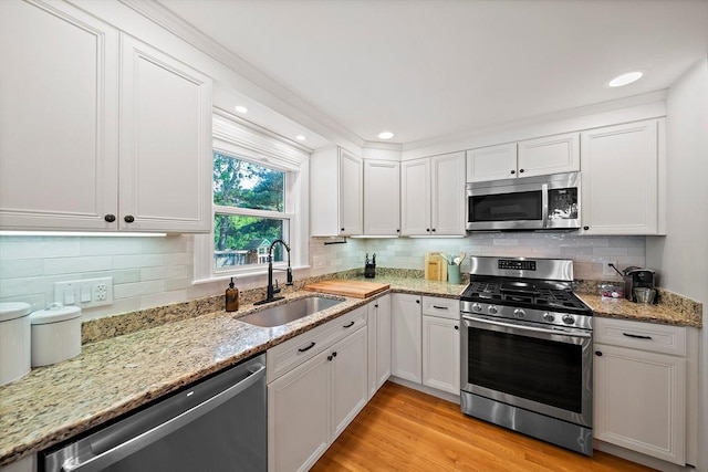 10 Stoughton Rd, Dedham, MA 02026 - kitchen with stainless steel appliances, a sink, white cabinets, backsplash, and recessed lighting
