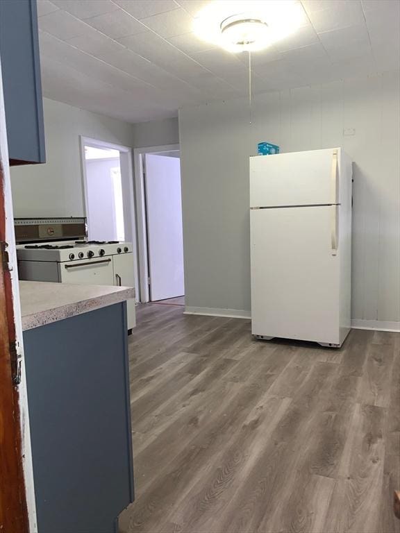 kitchen with white appliances, wood finished floors, baseboards, and light countertops