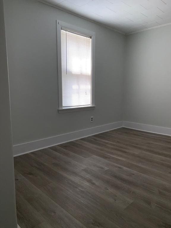 unfurnished room with dark wood-type flooring, baseboards, and crown molding