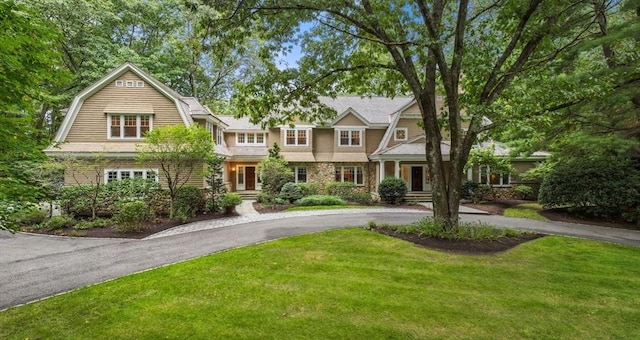 shingle-style home with curved driveway, a gambrel roof, and a front lawn