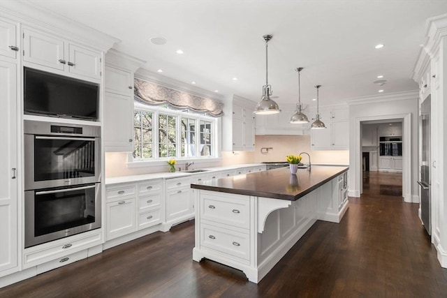kitchen with a sink, double oven, ornamental molding, white cabinetry, and dark wood-style floors