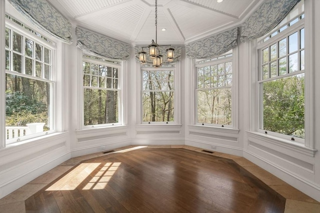 unfurnished sunroom featuring a healthy amount of sunlight, wood-type flooring, and a notable chandelier