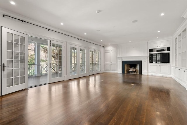 unfurnished living room with ornamental molding, wood finished floors, and a wealth of natural light