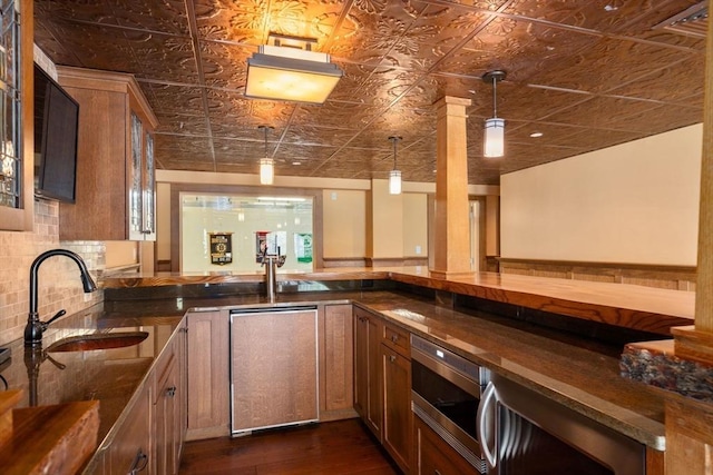 interior space featuring brown cabinetry, backsplash, a sink, an ornate ceiling, and stainless steel microwave