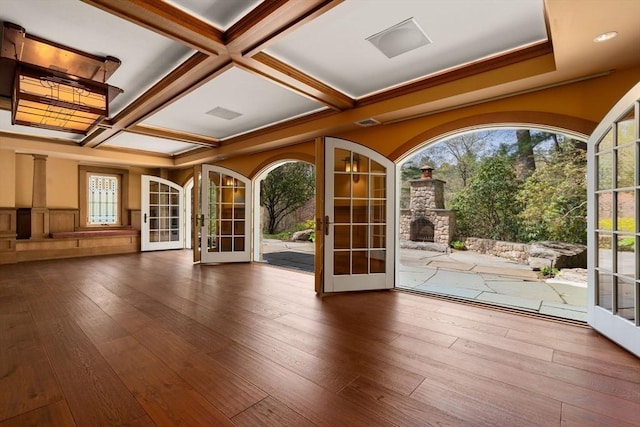 interior space featuring a healthy amount of sunlight, coffered ceiling, wood-type flooring, and french doors