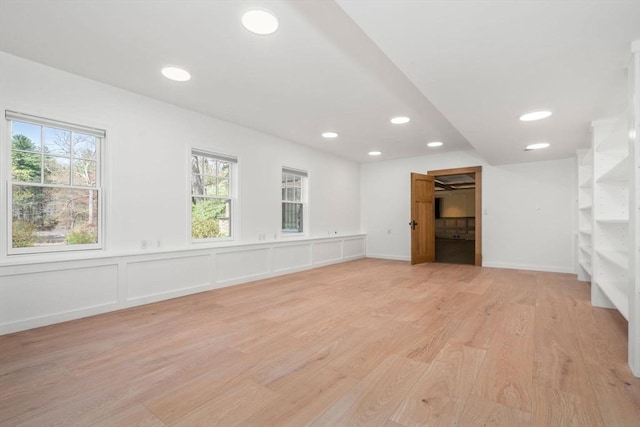 below grade area featuring recessed lighting, baseboards, a wealth of natural light, and light wood-type flooring