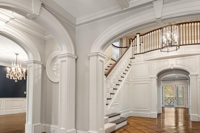 stairs featuring an inviting chandelier, arched walkways, a decorative wall, and ornate columns