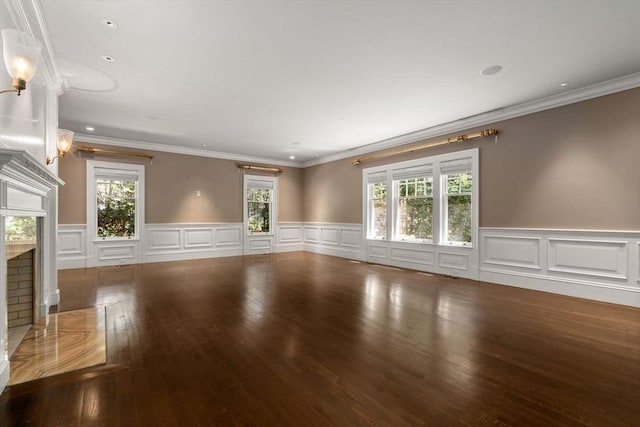 unfurnished living room featuring crown molding, a premium fireplace, wainscoting, and wood finished floors