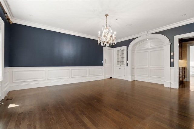 empty room featuring a decorative wall, wood finished floors, and a notable chandelier