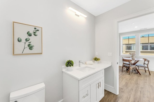 bathroom with baseboards, toilet, wood finished floors, and vanity