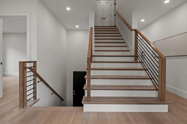 stairway featuring recessed lighting, wood finished floors, and baseboards
