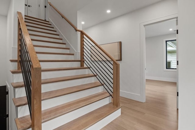 staircase with wood finished floors, recessed lighting, and baseboards