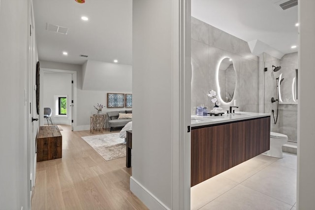 ensuite bathroom featuring a shower stall, double vanity, toilet, recessed lighting, and wood finished floors