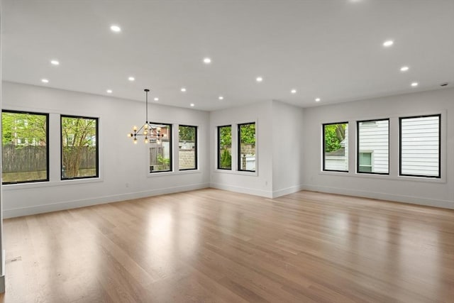 spare room featuring plenty of natural light, a chandelier, recessed lighting, and light wood-style flooring