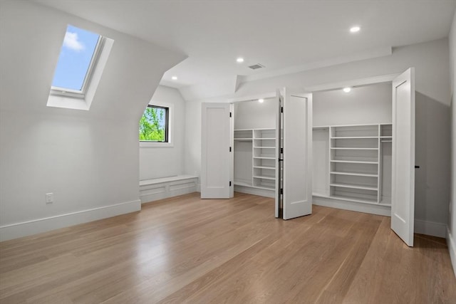 unfurnished bedroom with two closets, a skylight, light wood finished floors, lofted ceiling, and recessed lighting