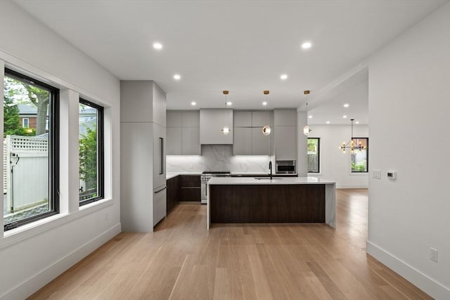 kitchen featuring modern cabinets, high end stainless steel range, a sink, light countertops, and light wood-type flooring
