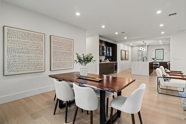 dining space featuring light wood-style flooring, beverage cooler, recessed lighting, and baseboards