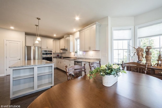 kitchen featuring open shelves, light stone countertops, a sink, stainless steel appliances, and dark wood-type flooring